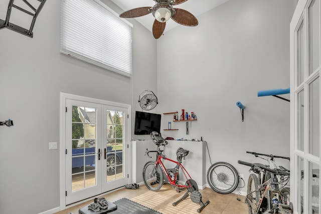 workout room featuring french doors, ceiling fan, light tile patterned flooring, and a high ceiling