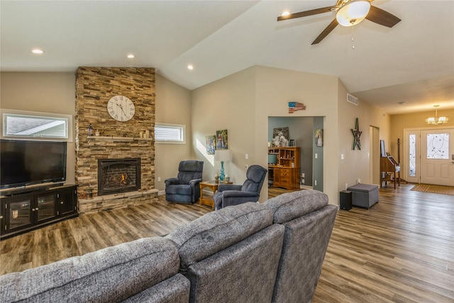 living room with ceiling fan, hardwood / wood-style flooring, vaulted ceiling, and a stone fireplace