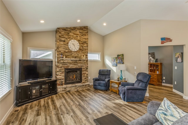 living room with high vaulted ceiling, a stone fireplace, and wood-type flooring