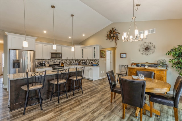 dining room with sink, a notable chandelier, hardwood / wood-style flooring, and high vaulted ceiling