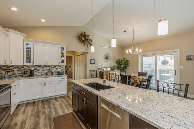 kitchen featuring sink, hardwood / wood-style floors, vaulted ceiling, decorative light fixtures, and white cabinets