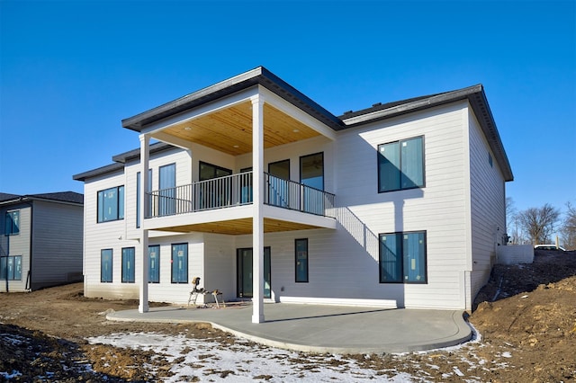 snow covered house with a patio area and a balcony