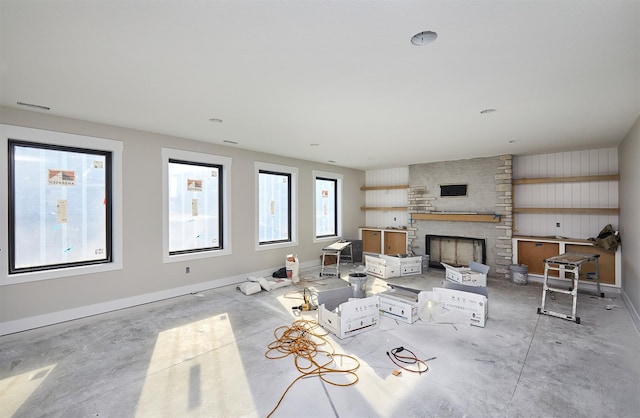 living room featuring plenty of natural light and a stone fireplace