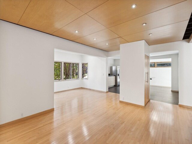 spare room featuring recessed lighting, hardwood / wood-style flooring, and baseboards