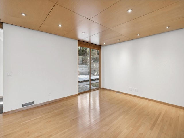 empty room featuring wood finished floors, visible vents, and baseboards