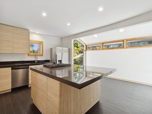 kitchen with a sink, appliances with stainless steel finishes, dark countertops, and light brown cabinets