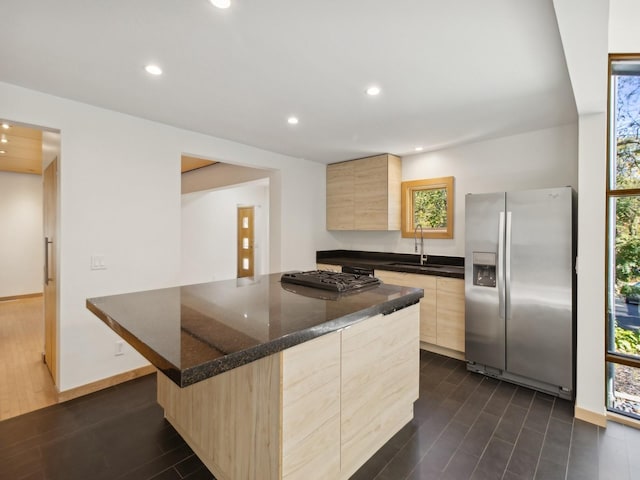 kitchen with stainless steel fridge, modern cabinets, wood tiled floor, light brown cabinets, and a sink