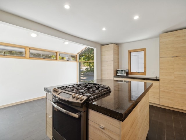 kitchen featuring stainless steel gas stove, light brown cabinetry, and modern cabinets