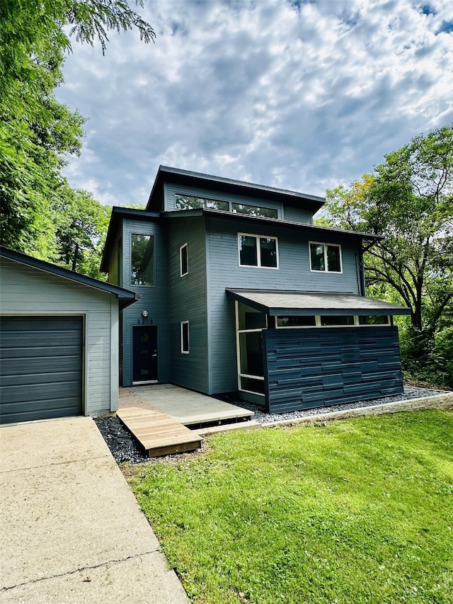 view of front facade featuring a garage, concrete driveway, a front lawn, and a deck