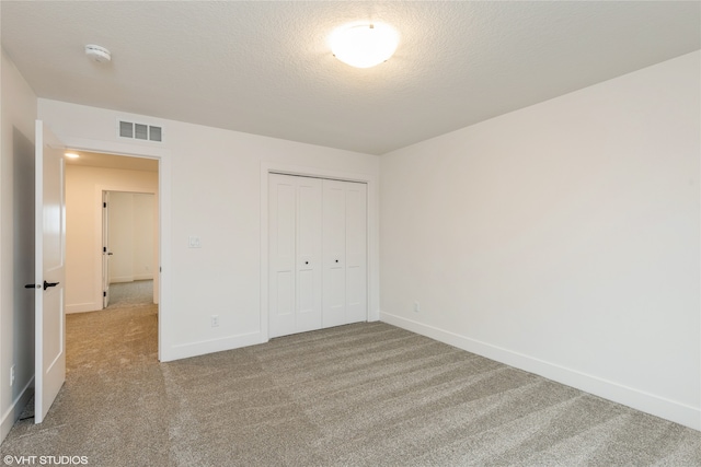 unfurnished bedroom with a textured ceiling, light colored carpet, and a closet