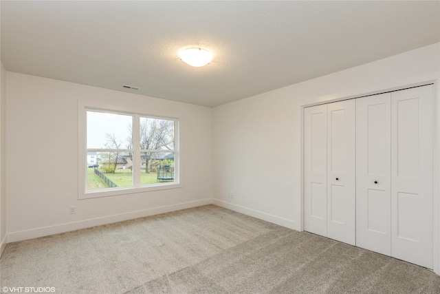 unfurnished bedroom featuring a closet, light colored carpet, and a textured ceiling