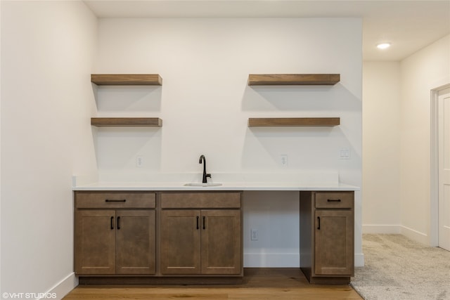 kitchen with sink, dark brown cabinets, and light hardwood / wood-style floors