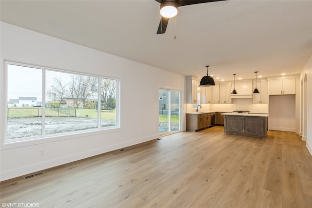 kitchen with a center island, decorative light fixtures, white cabinetry, and light hardwood / wood-style floors