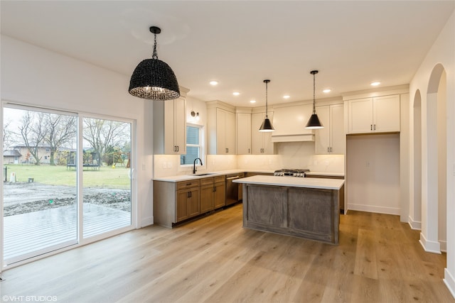 kitchen featuring stainless steel appliances, hanging light fixtures, a center island, and light wood-type flooring