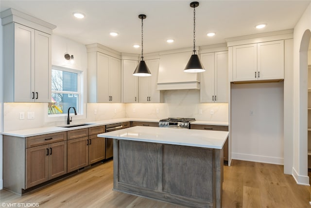 kitchen with stainless steel appliances, a kitchen island, light hardwood / wood-style floors, and sink