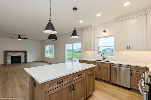 kitchen featuring a wealth of natural light, hanging light fixtures, stainless steel dishwasher, and sink