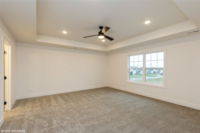 carpeted empty room with a tray ceiling and ceiling fan