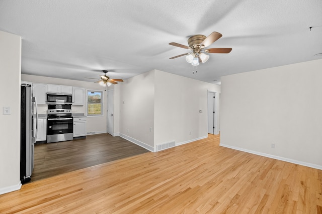 unfurnished living room featuring light hardwood / wood-style flooring, a textured ceiling, and ceiling fan