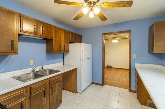 kitchen with ceiling fan, white fridge, and sink