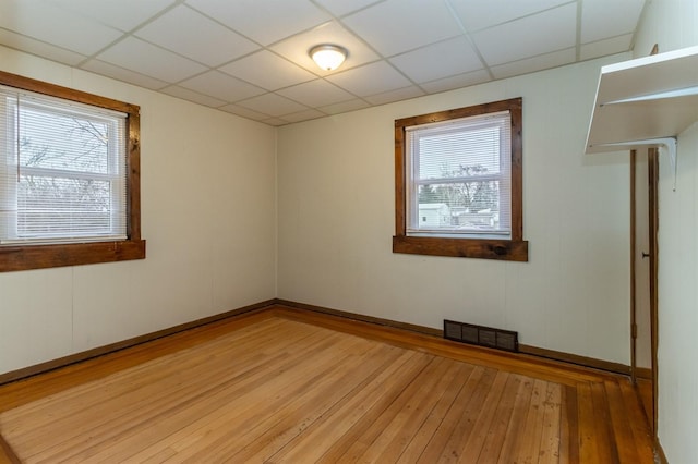 spare room with hardwood / wood-style floors, a paneled ceiling, and plenty of natural light