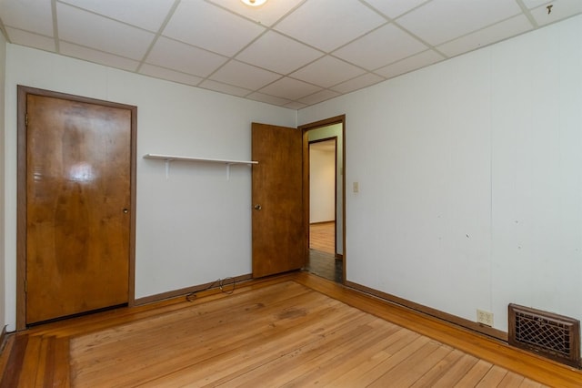 unfurnished bedroom with a paneled ceiling, a closet, and light wood-type flooring