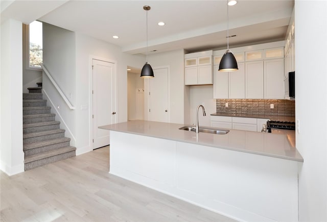 kitchen with white cabinetry, range, sink, and hanging light fixtures