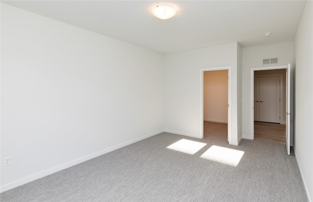 unfurnished bedroom with a spacious closet, a closet, and light colored carpet