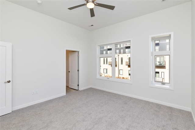 carpeted spare room featuring ceiling fan and plenty of natural light