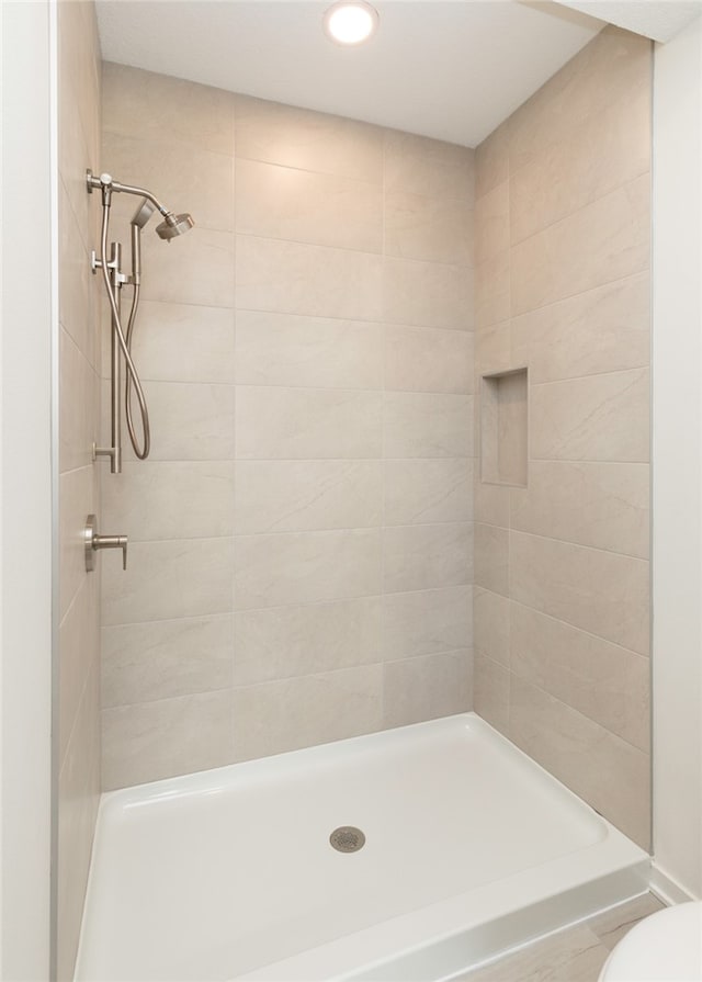 bathroom with tiled shower and toilet