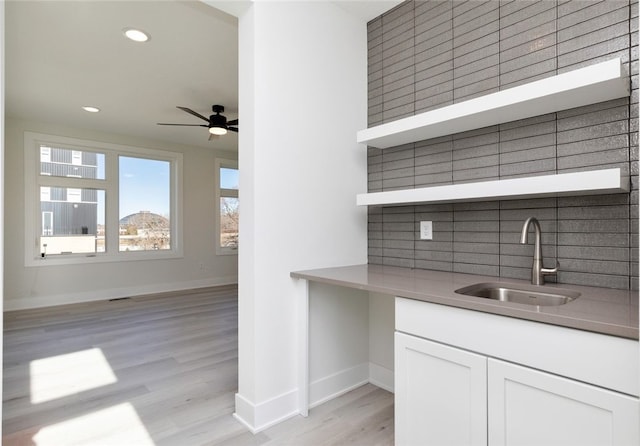 kitchen featuring decorative backsplash, sink, light wood-type flooring, and white cabinets