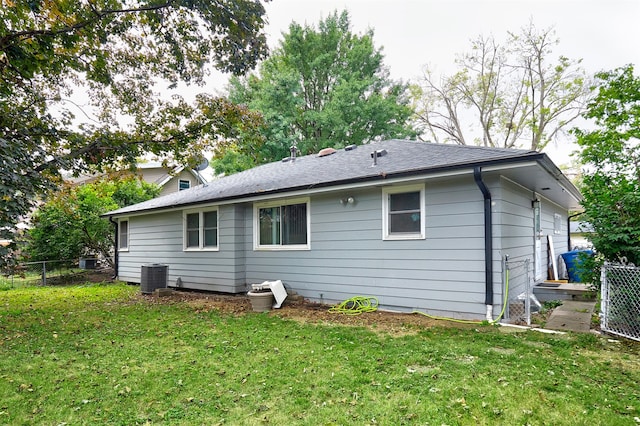 rear view of property featuring a lawn and central AC unit