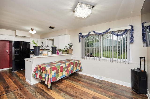 interior space with dark hardwood / wood-style flooring, white cabinetry, kitchen peninsula, and black fridge