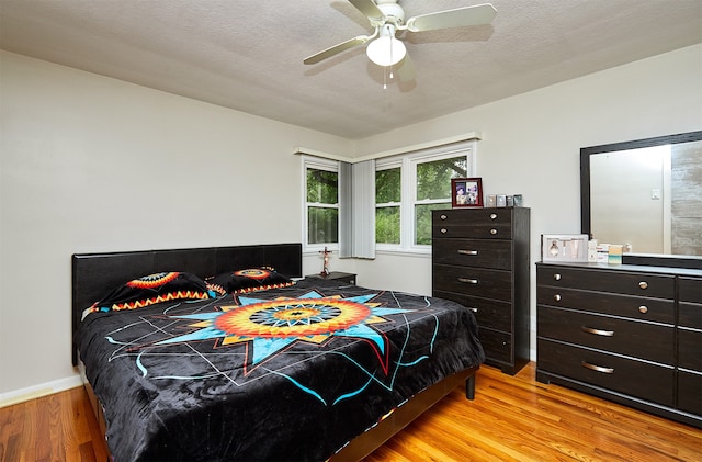 bedroom featuring ceiling fan, a textured ceiling, and light wood-type flooring