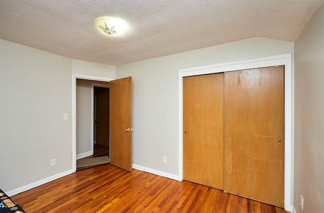 unfurnished bedroom with a closet, wood-type flooring, and a textured ceiling