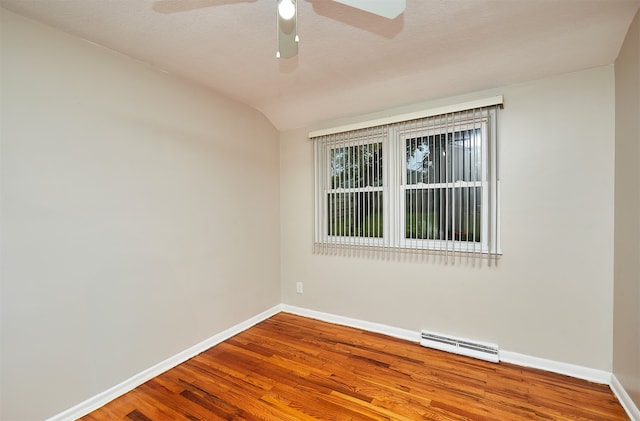 empty room featuring hardwood / wood-style flooring, baseboard heating, vaulted ceiling, a textured ceiling, and ceiling fan