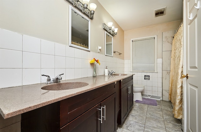 bathroom featuring toilet, vanity, tile patterned floors, and tile walls