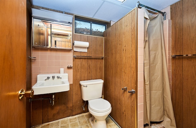 bathroom with tile walls, sink, curtained shower, and toilet