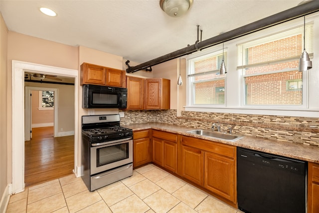 kitchen with light tile patterned floors, sink, black appliances, and decorative backsplash