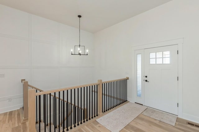 entryway with hardwood / wood-style floors and an inviting chandelier