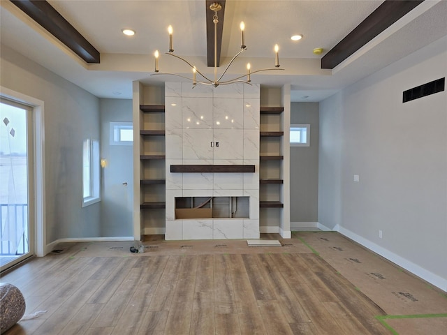 unfurnished living room with hardwood / wood-style flooring, a healthy amount of sunlight, and a tray ceiling