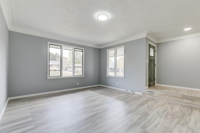 spare room featuring ornamental molding, light hardwood / wood-style flooring, and plenty of natural light