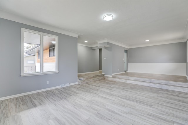 spare room featuring wood finished floors, visible vents, ornamental molding, and baseboards