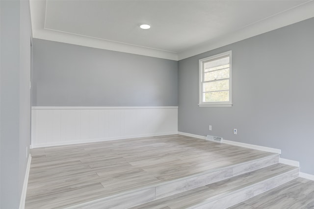 empty room with crown molding and light hardwood / wood-style flooring