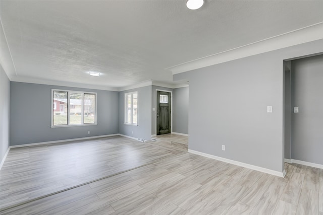 spare room with a textured ceiling and light hardwood / wood-style flooring