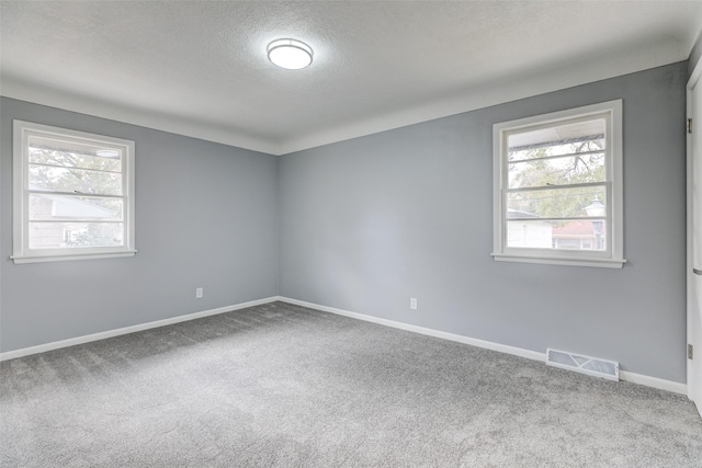empty room featuring baseboards, visible vents, a textured ceiling, and carpet flooring