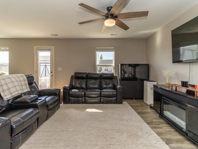 living room with ceiling fan, visible vents, wood finished floors, and a wealth of natural light