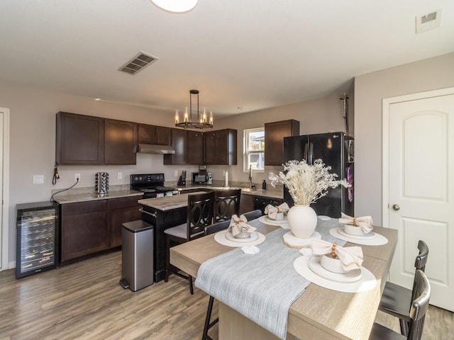 kitchen featuring black appliances, wine cooler, visible vents, and dark brown cabinets