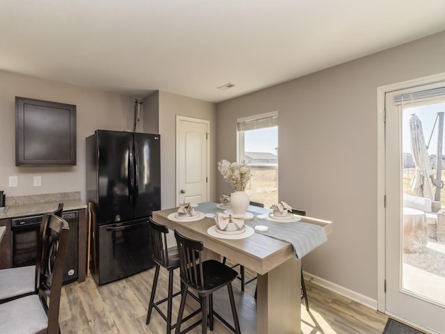 dining area with light wood-style flooring, visible vents, and a wealth of natural light