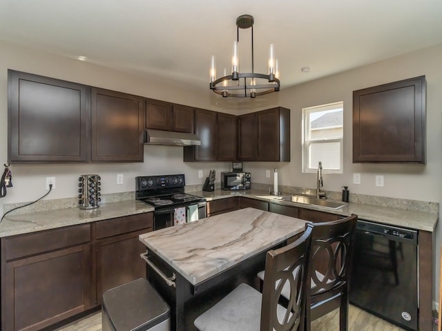 kitchen featuring decorative light fixtures, a sink, dark brown cabinets, under cabinet range hood, and black appliances