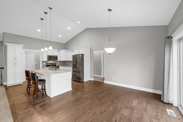 kitchen with white cabinetry, stainless steel appliances, pendant lighting, dark hardwood / wood-style floors, and a kitchen island with sink